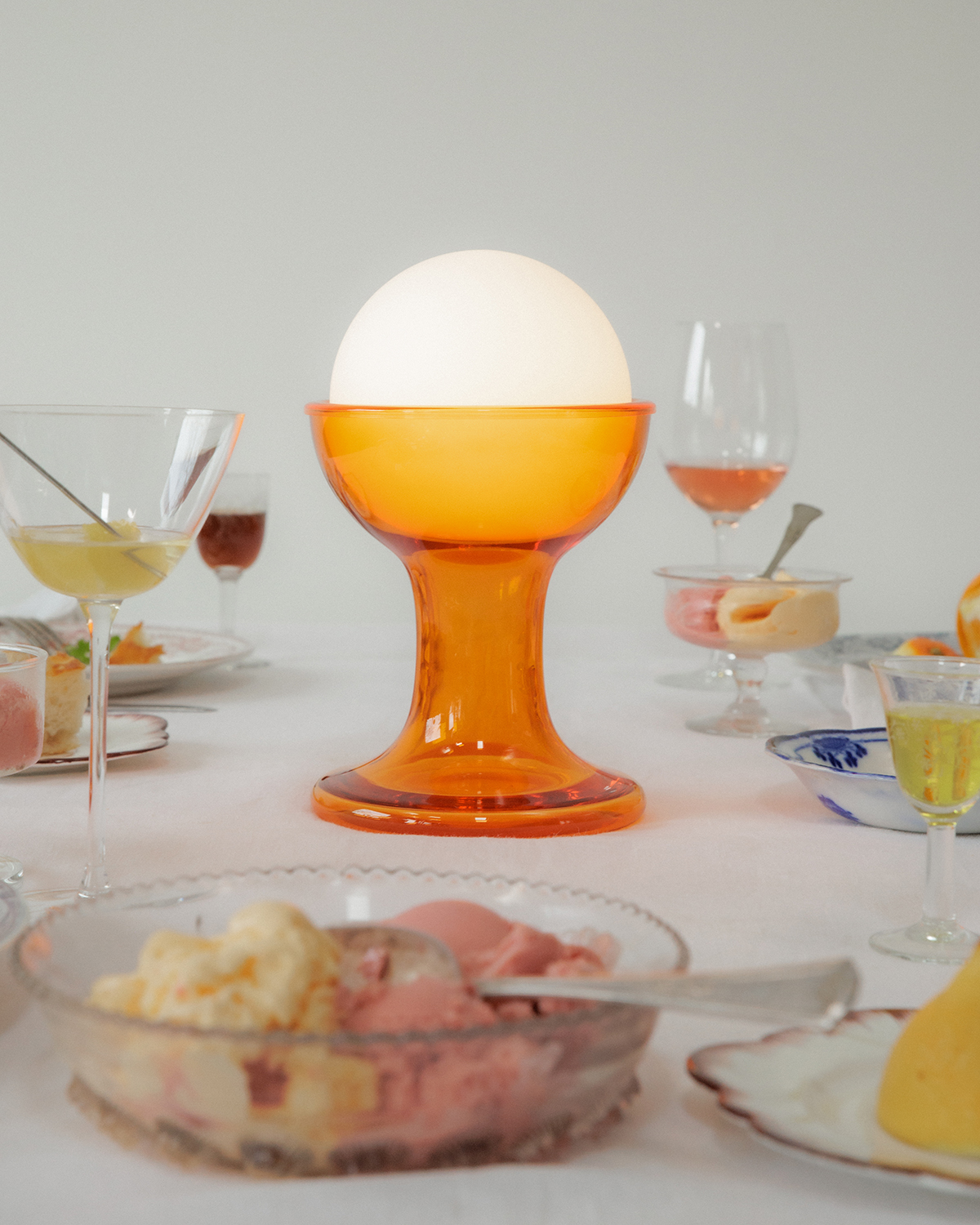 Orange Gelato lamp by Established and Sons on a dining table next to plates and wine glasses
