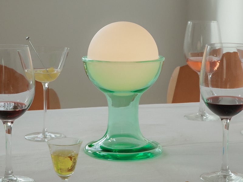 Green Gelato lamp by Established and Sons on a dining table next to wine glasses