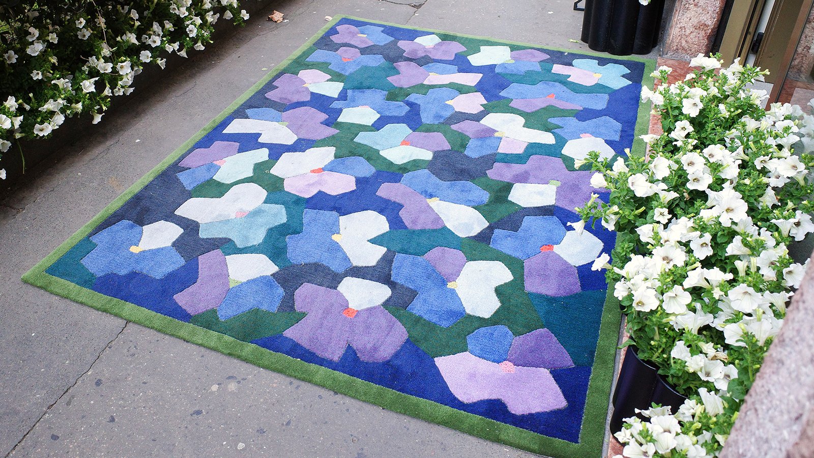 Anemon rug by Kasthall next to a bed of white flowers