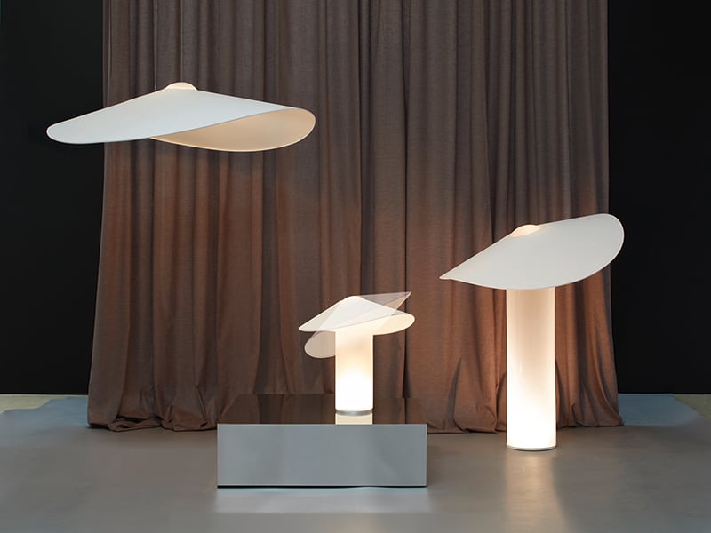 Three Loji lamps by Migard in front of a brown curtain and the shortest lamp on a platform
