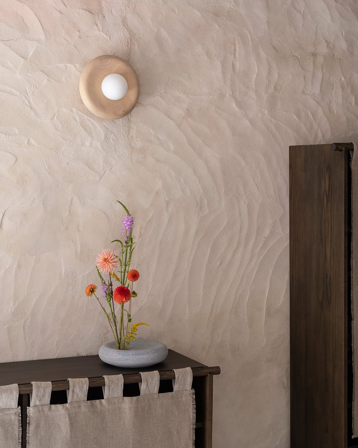 Cabinet and table with flowers on top, Nest lamp by Origin Made on the beige wall