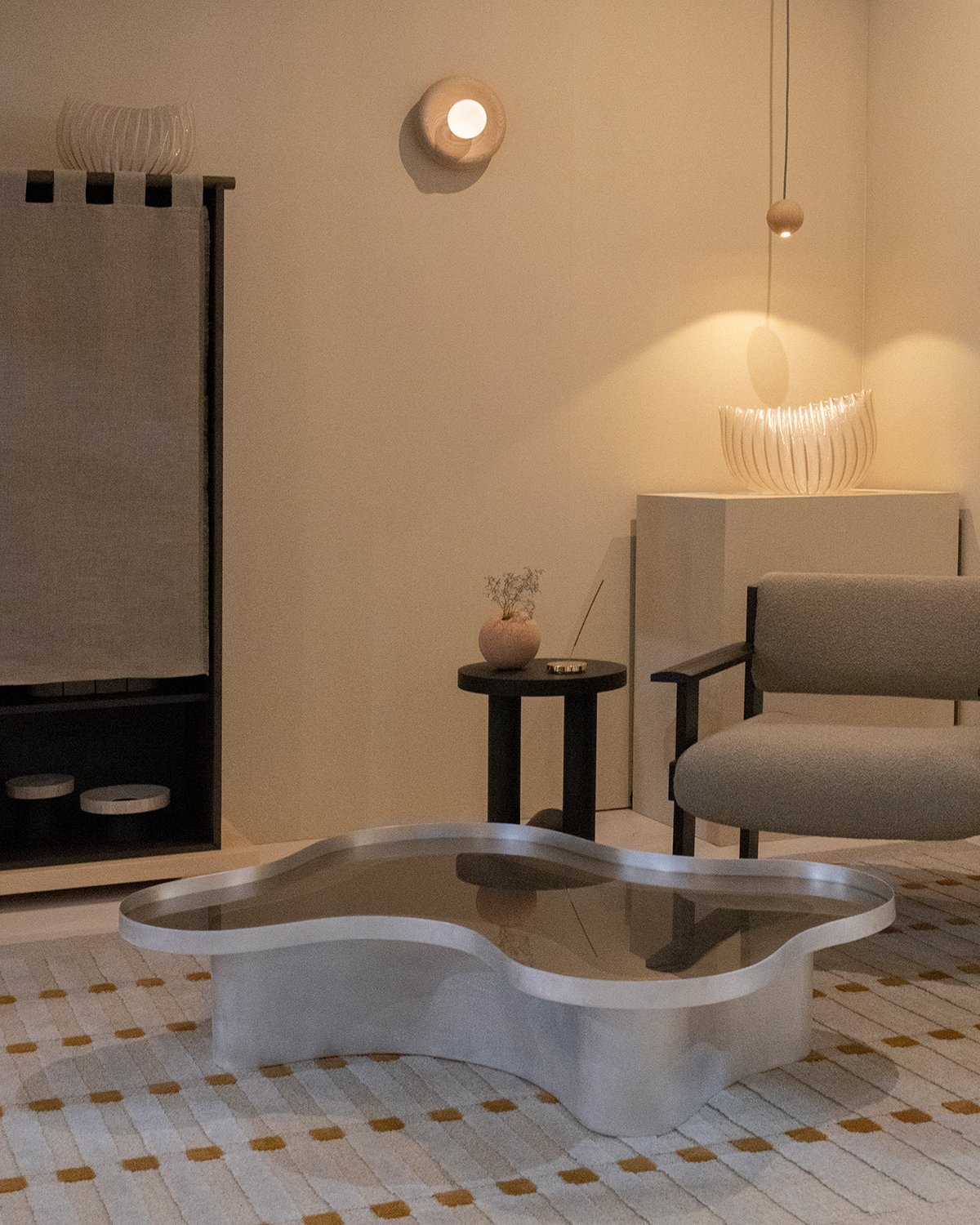 Organically-shaped coffee table and couch with the Nest lamp by Origin Made on a wall