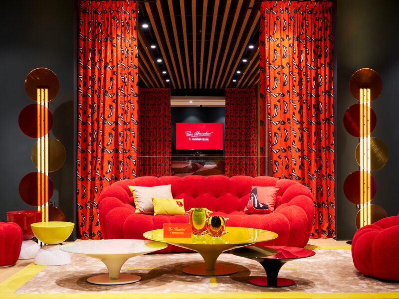 Roche Bobois vibrant furniture collection with a red sofa, yellow, white and red coffee tables and red curtains.