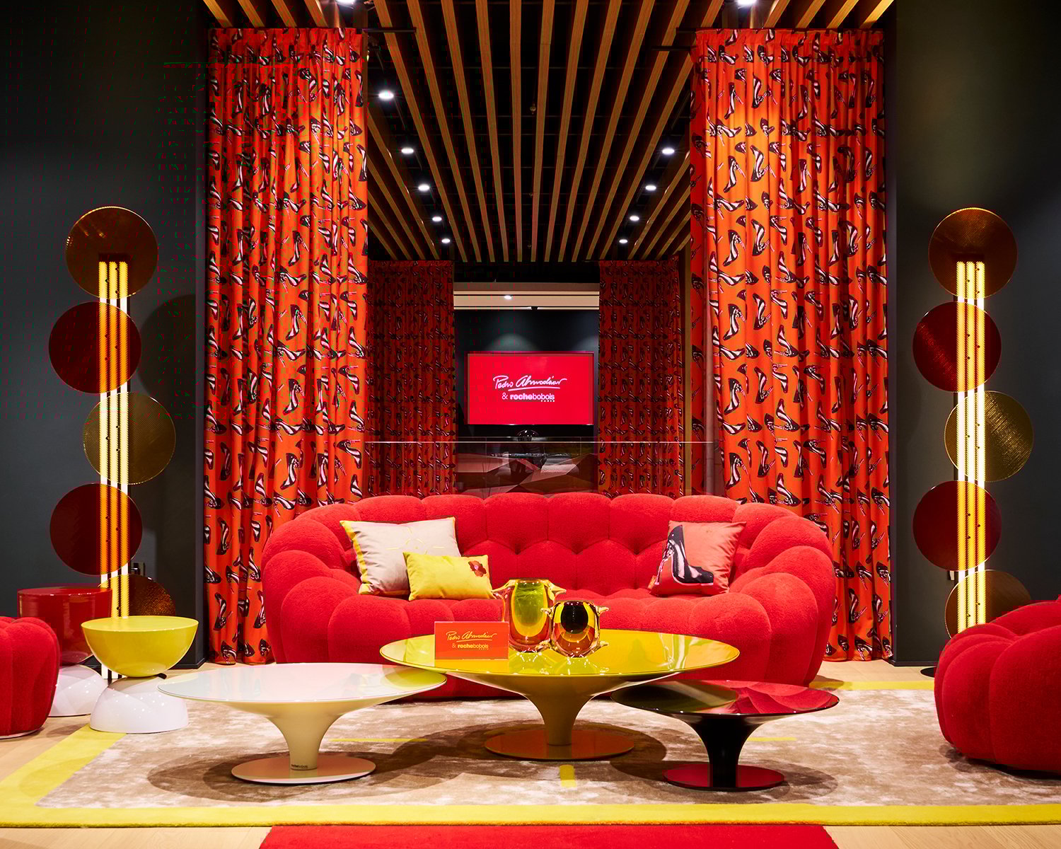 Roche Bobois vibrant furniture collection with a red sofa, yellow, white and red coffee tables and red curtains.