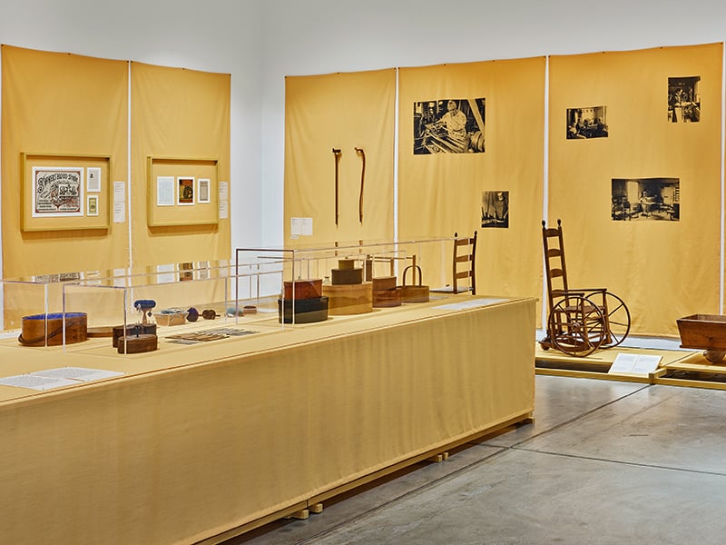 Shaker design museum exhibition - Yellow drapes on a wall and tablecloth with historic objects displayed