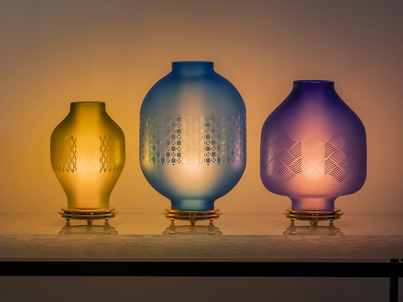 Dimly lit room with three differently sized and coloured lanterns by the goodman studio