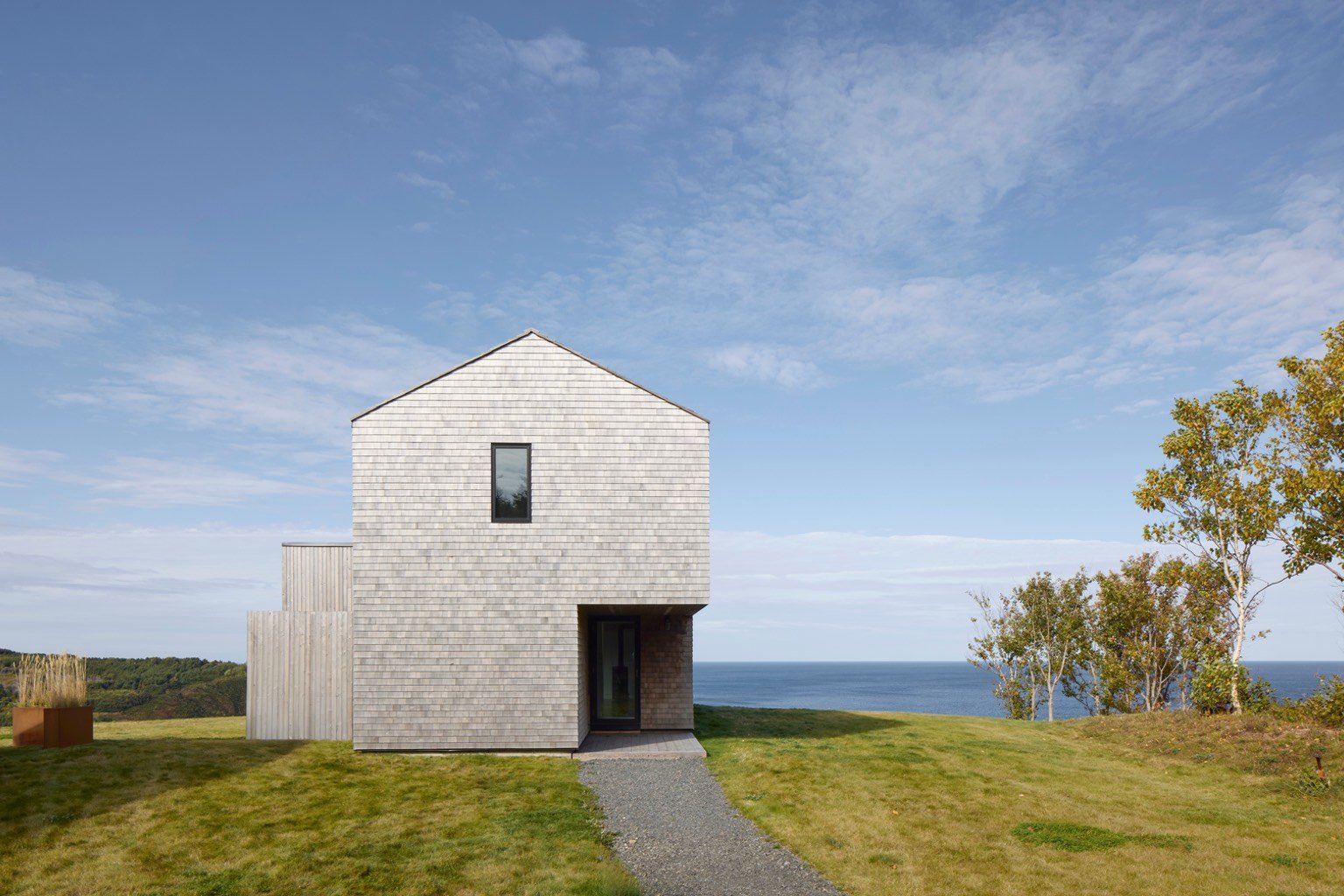 A grey cedar cabin with a pitched roof looks out to the Northumberland Strait.