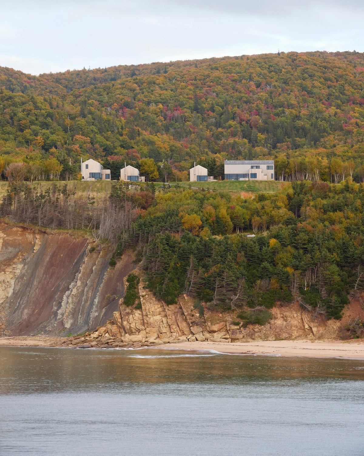 Four modern coastal rental cabins sit on a hill above the ocean.
