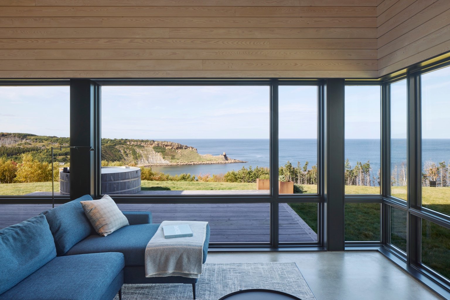 A blue sofa looks out wraparound windows to the Northumberland Strait.
