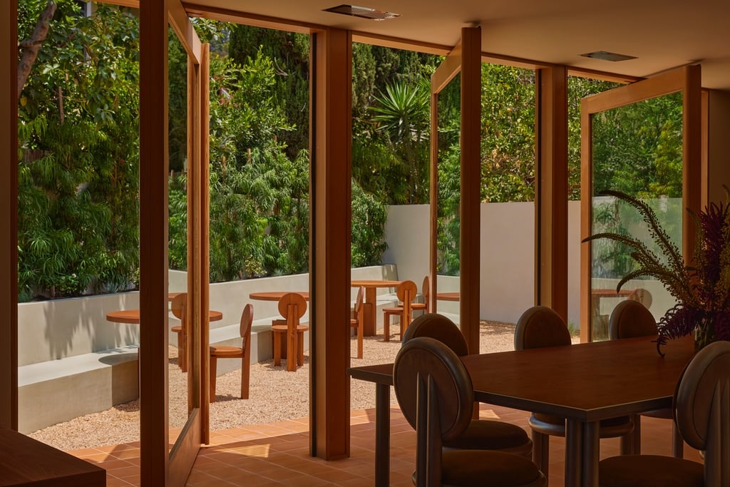 An office design by 22RE for LA creative agency Day Job features a wall of patio doors that are rotated open to step out to a leafy private courtyard.