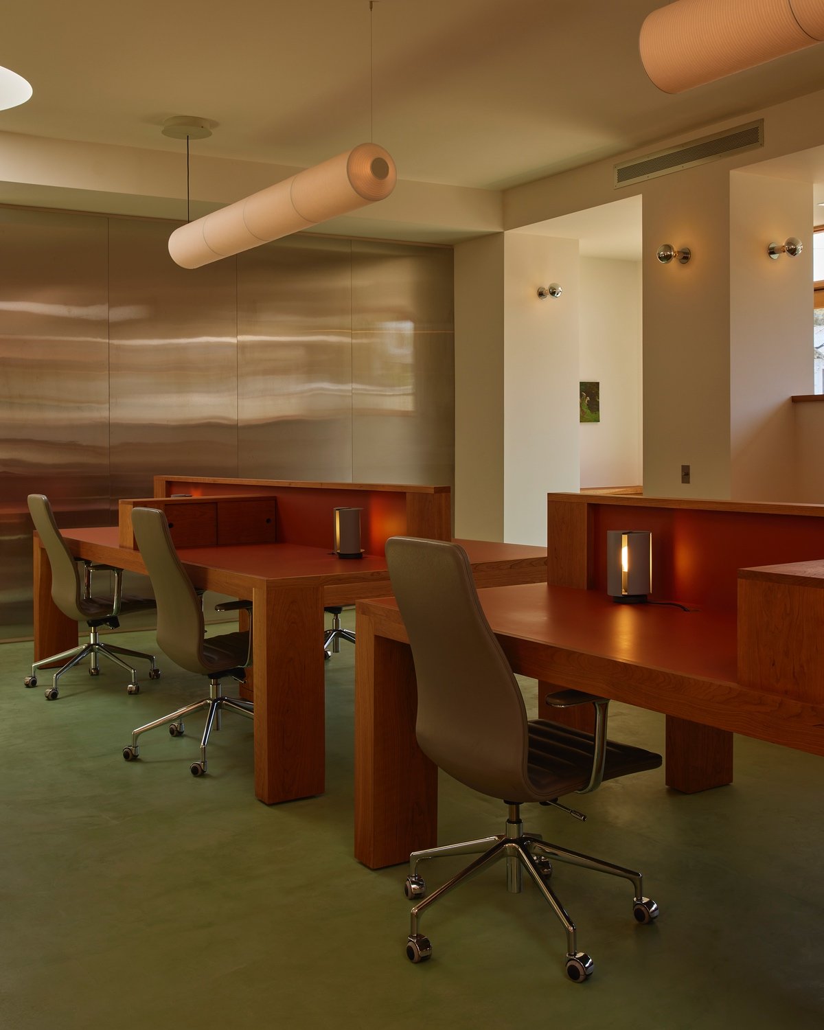 An office design by 22RE for LA creative agency Day Job features green office chairs seated at a blocky wooden desk.