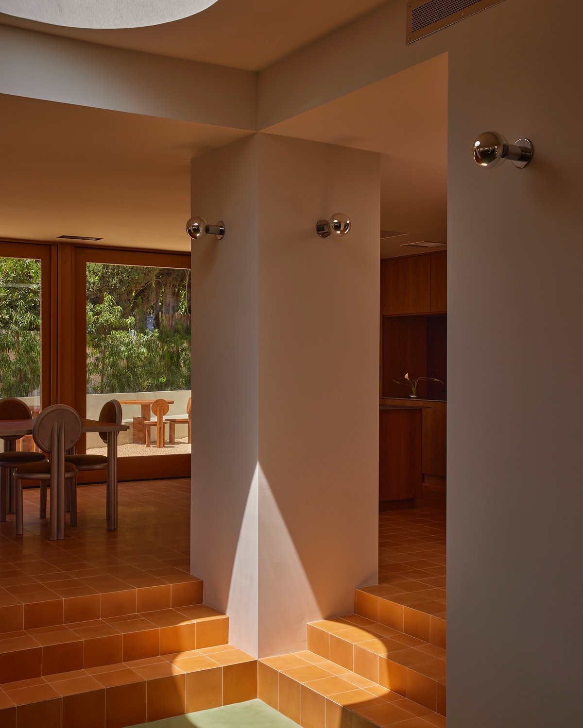 An office area features large blocky columns and orange floor tiles that step down into a sunken lower area.