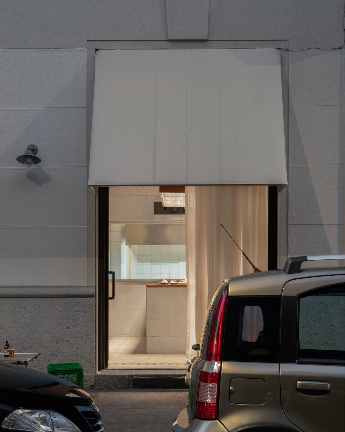 Looking through a window with a cream-coloured curtain into the bar inside.