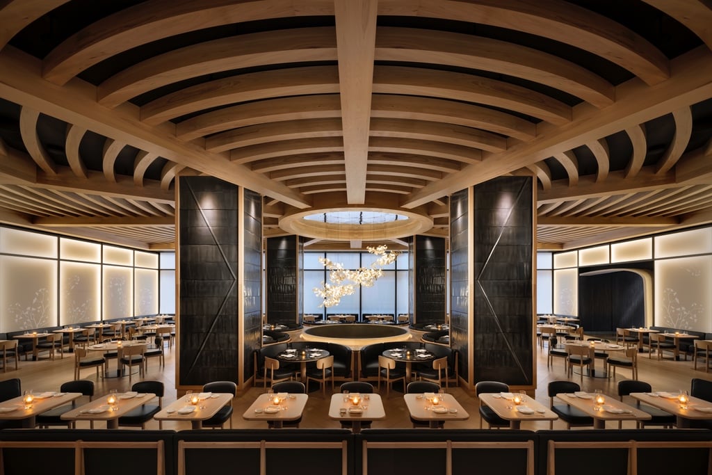 The dining room at Nobu Toronto featuring circular timber frames that lead to a central opening with a ceramic artwork hanging down.