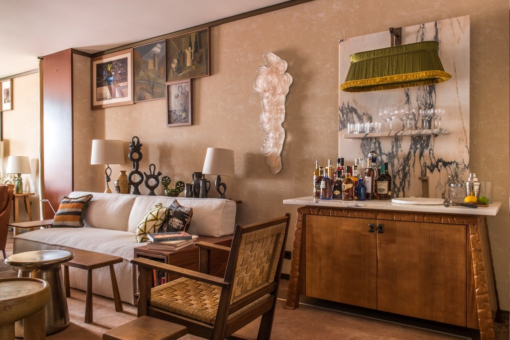 A guest room at the Brach Madrid hotel designed by Philippe Starck features a wooden bar with a wide pendant featuring a green fabric lampshade hanging above it.