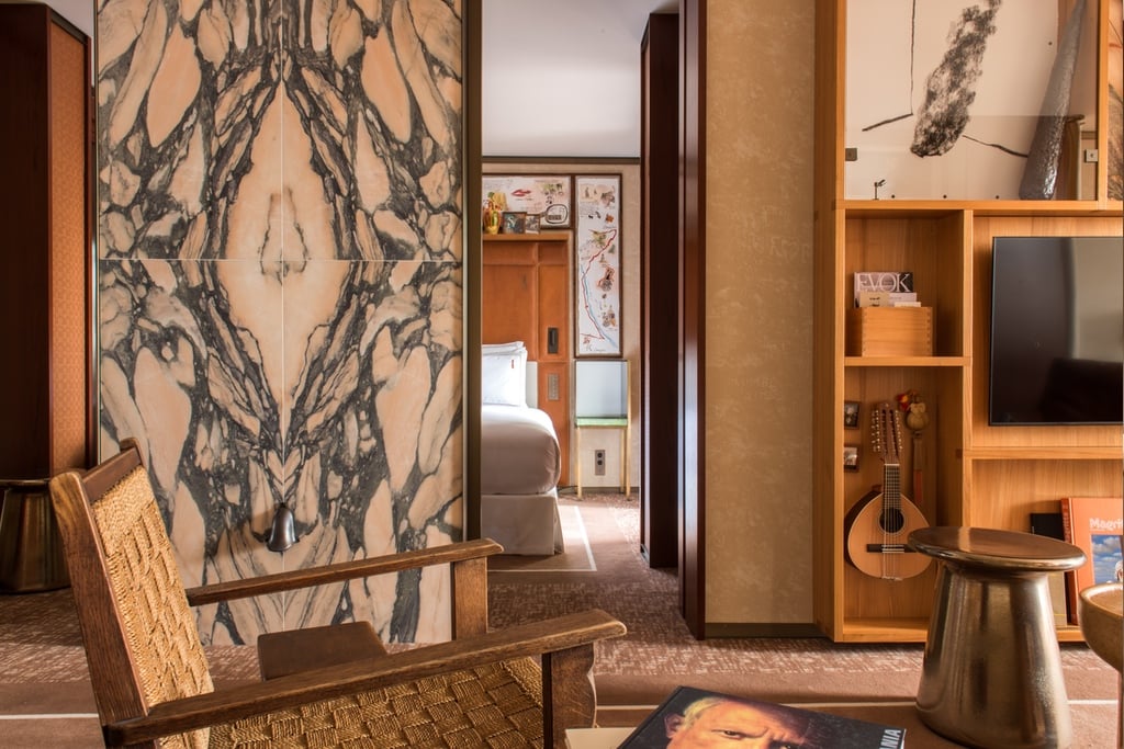 A guest room at the Brach Madrid hotel designed by Philippe Starck features a large partition clad in marble with a cane chair in front of it.