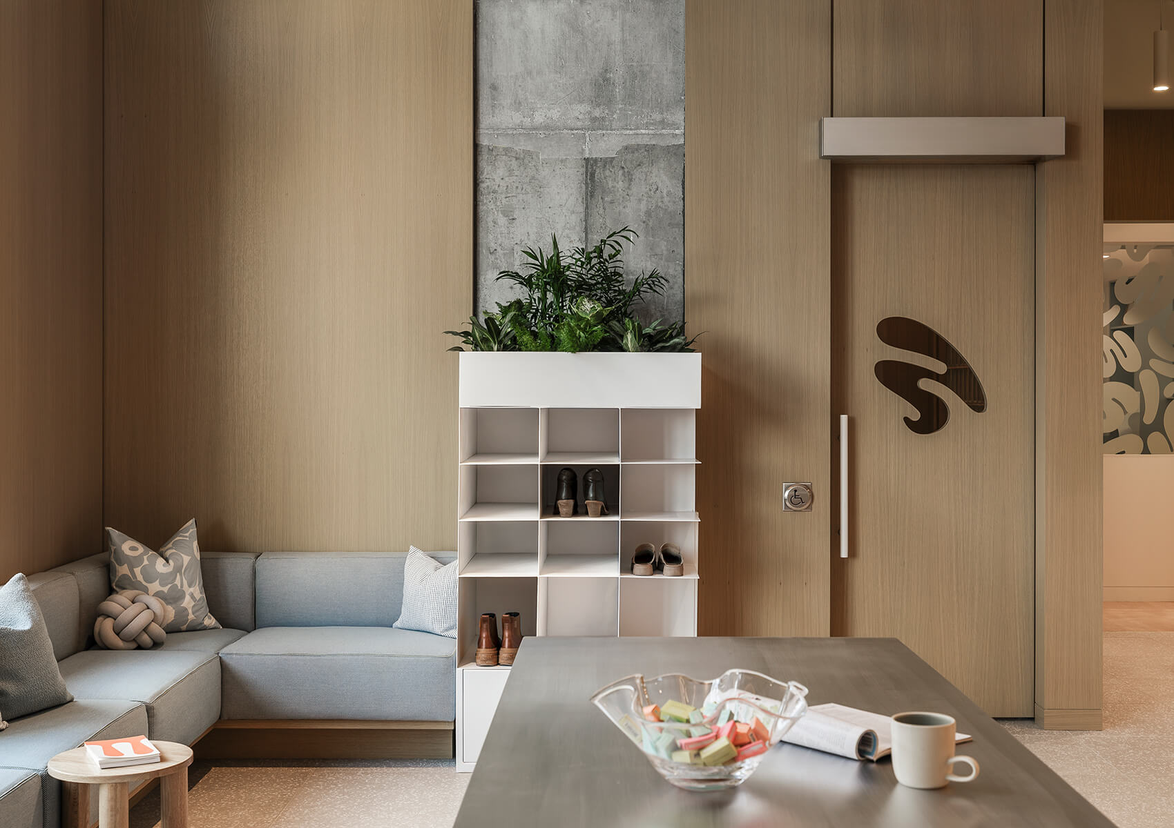 Dental clinic waiting room with wood walls and grey wraparound sofa