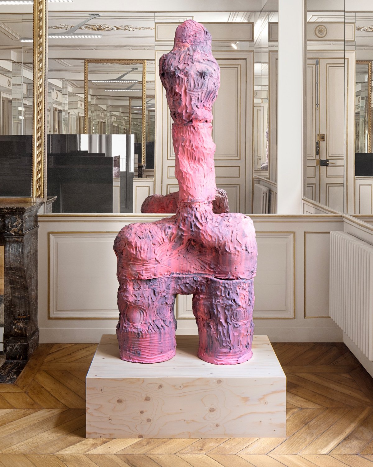 A pink sculpture with two legs that merge into one central column extending upwards.