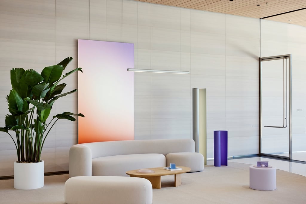 A rounded white sofa designed by Sabine Marcelis in front of a gradient panel in a room at Apple headquarters in Cupertino.