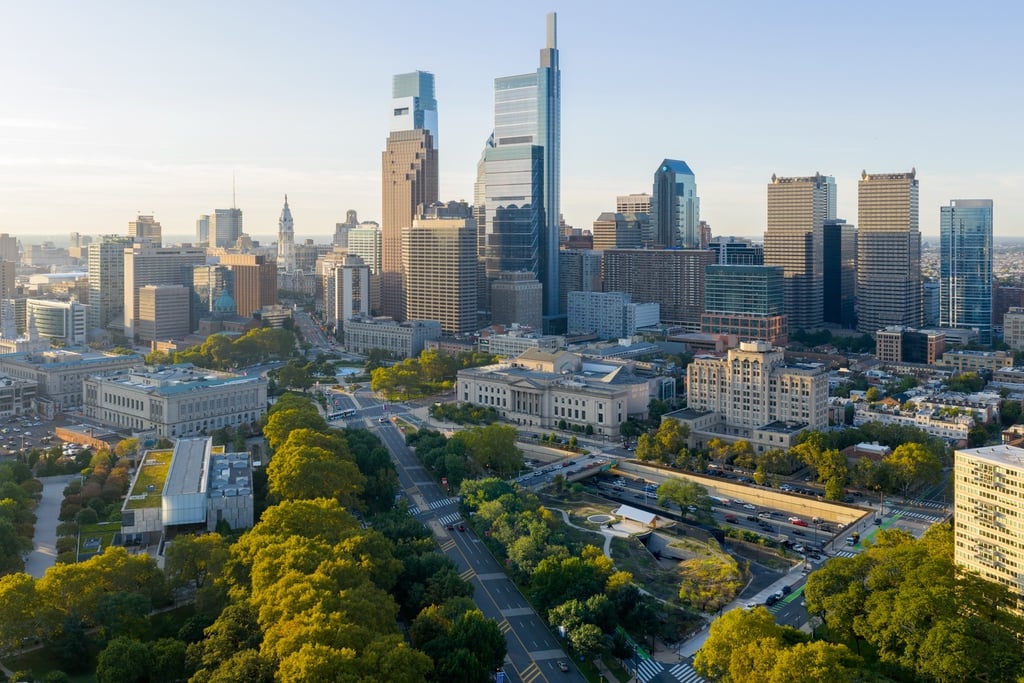 An aerial view of Calder Gardens in Philadelphia, showing the trapezoidal mirrored building amongst the city's skyline and Benjamin Franklin Parkway.