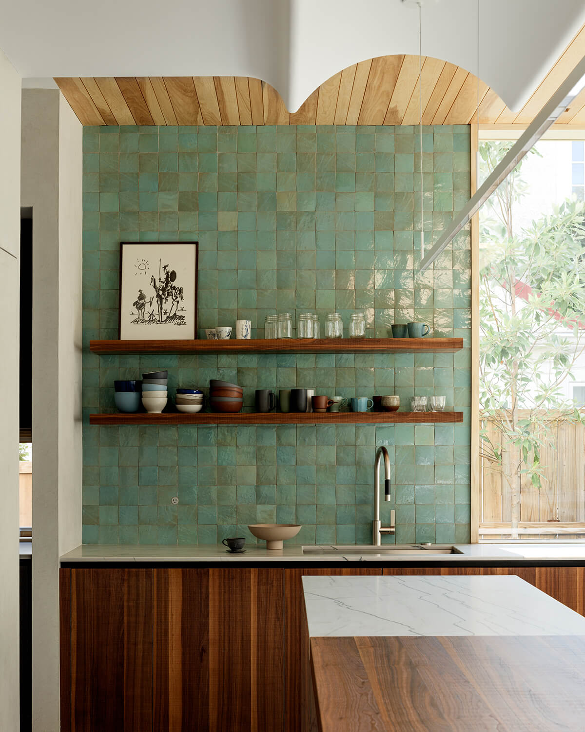 A mix of materials — warm pine ceiling planks, dramatic quartzite counters, rich walnut cabinets and hand-made tiles — creates a layered and inviting backdrop for busy family life.