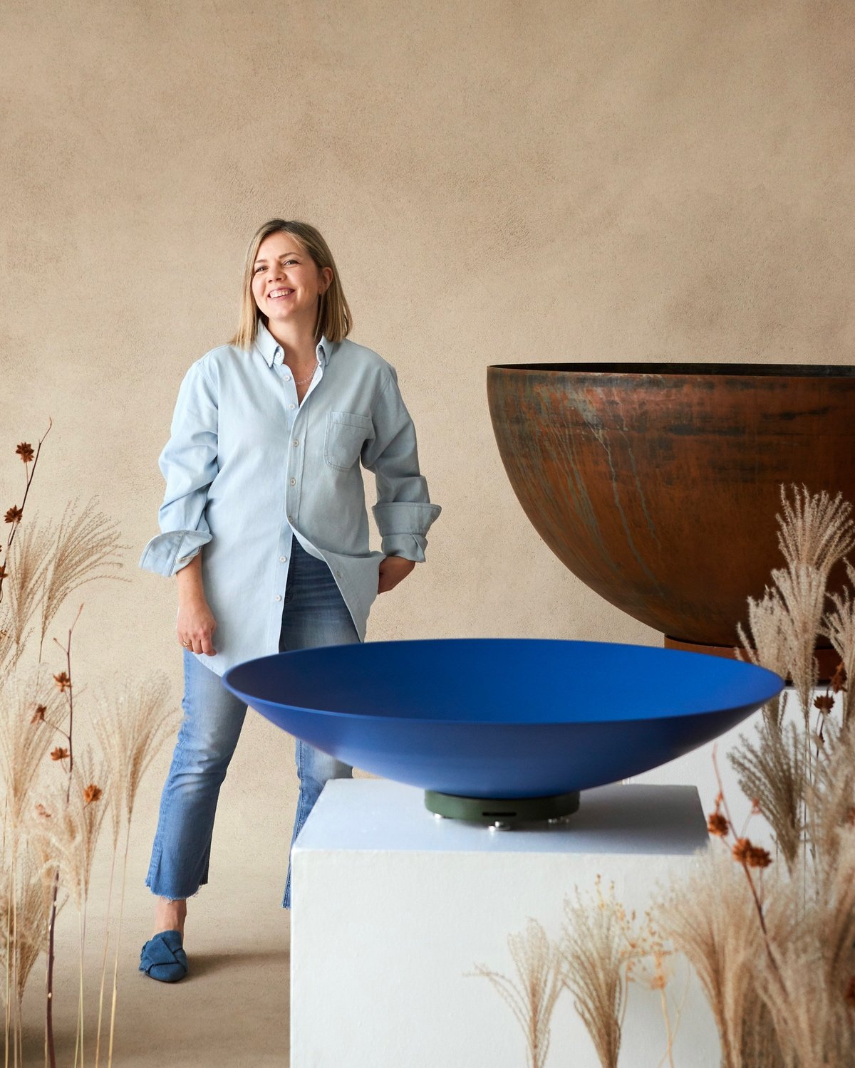 Landscape architect Kate Fox-Whyte standing next to a shallow blue and deep Corten steel planter from her Été collection of made-in-Canada outdoor products.