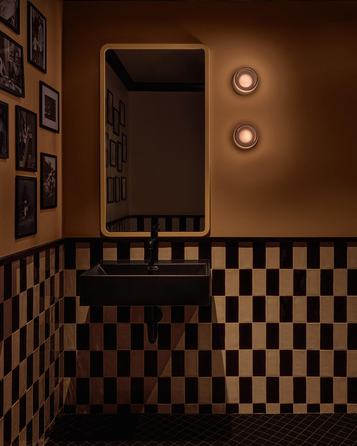 Bathroom with black and cream checkered tile and family photos on the walls