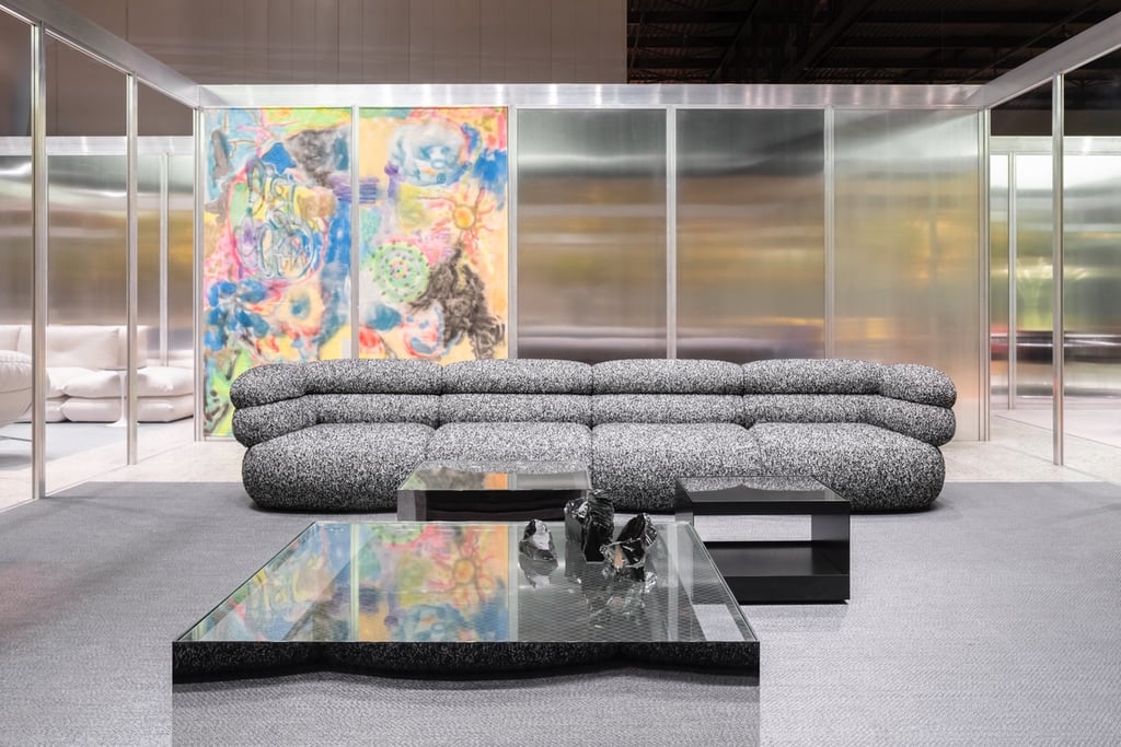 The curved Biboni sofa by Johnston Marklee for Knoll shown in a pavilion at the Milan Furniture Fair in front of a wall with colourful graffiti-style art.