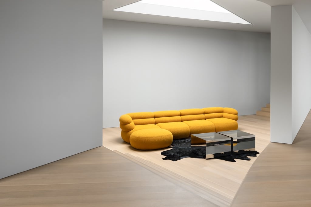 A yellow version of the Biboni sofa by Johnston Marklee for Knoll in a white room with a skylight overhead.