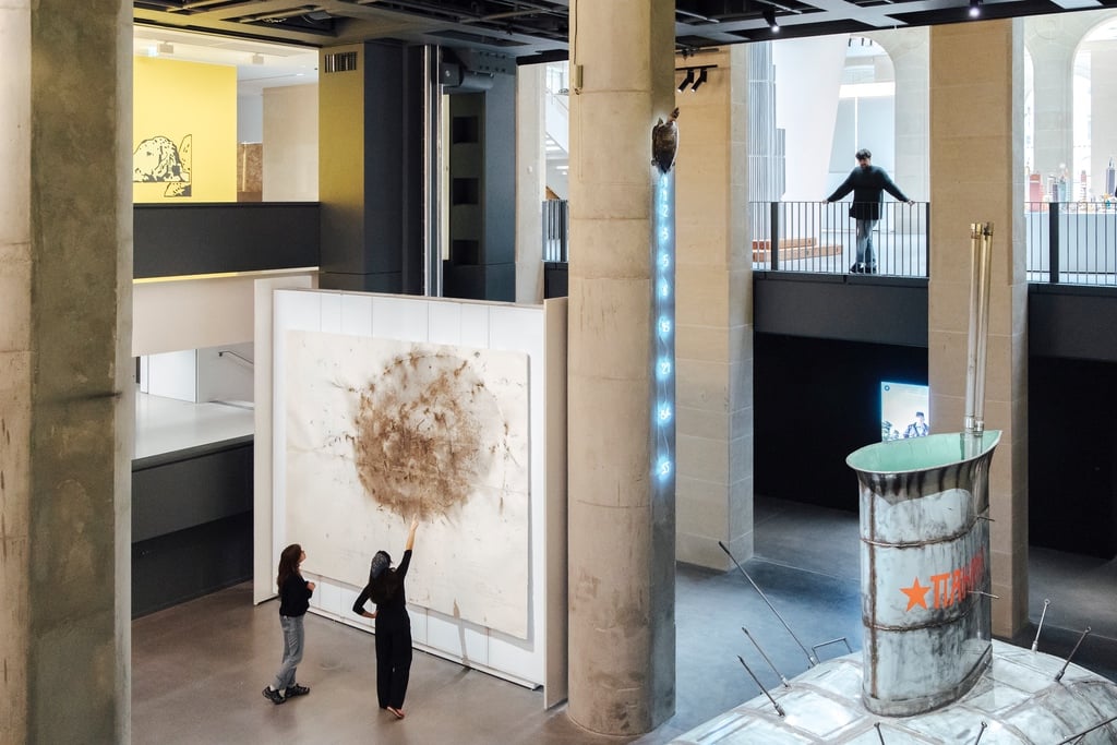 Two people point at a large abstract artwork on a display wall inside a triple-height museum space with large concrete columns at the Fondation Cartier designed by Jean Nouvel, one of the best architecture projects of 2025.