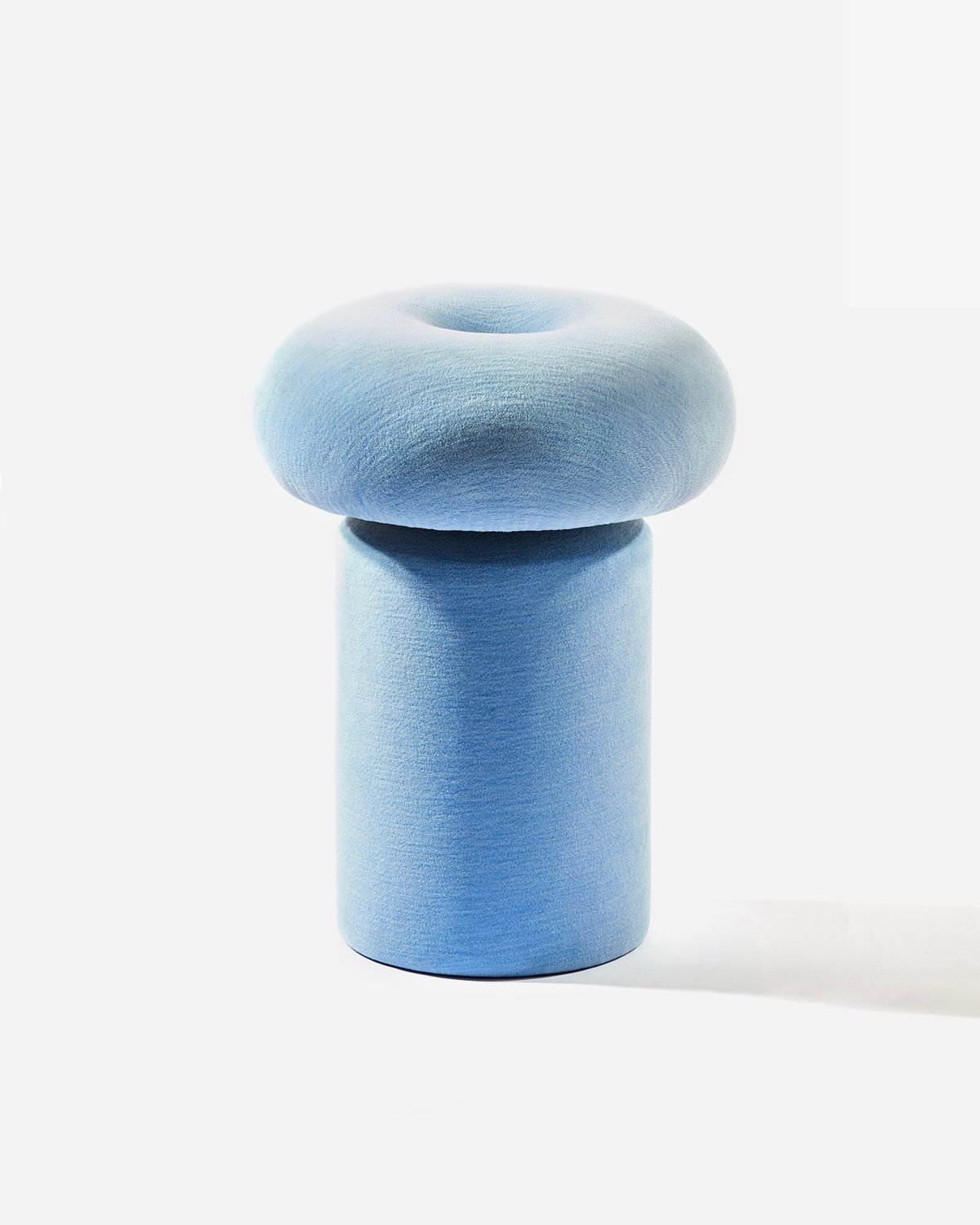 A light blue upholstered stool with a circular top and cylindrical base.
