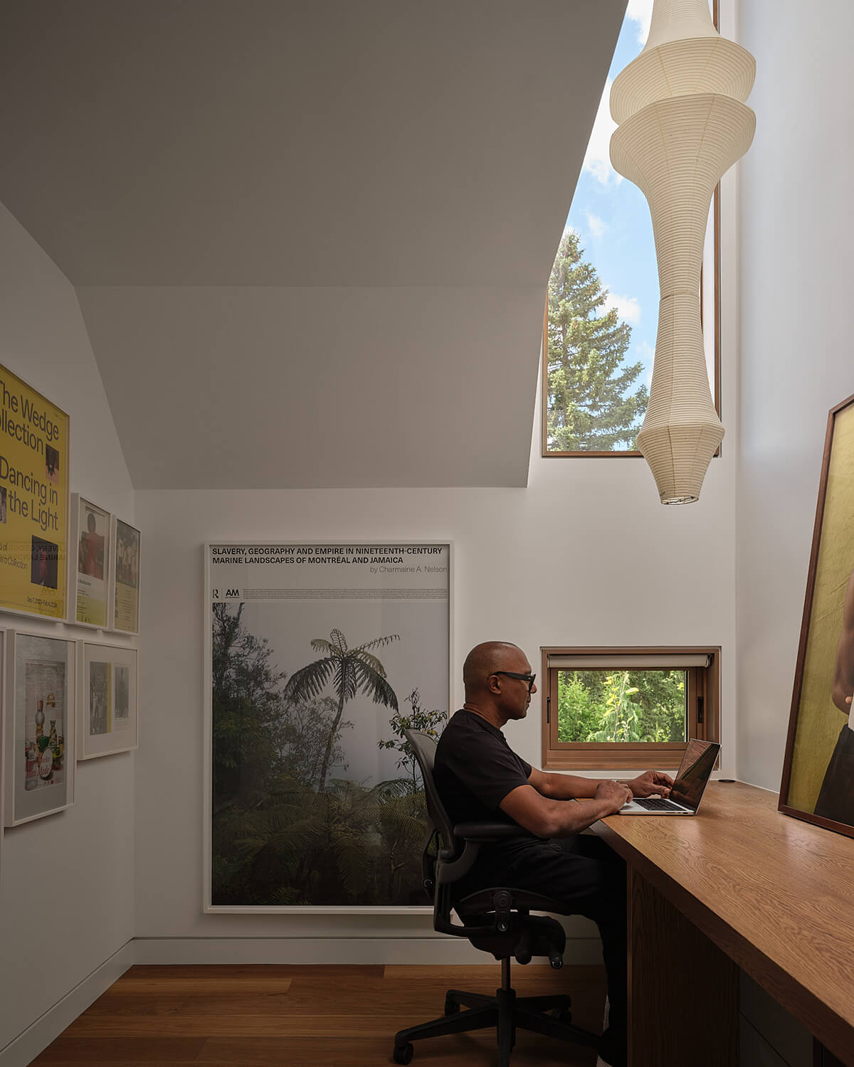 Montague's office is lit by a soaring double-height window; a sculptural pendant lamp hangs above the desk.