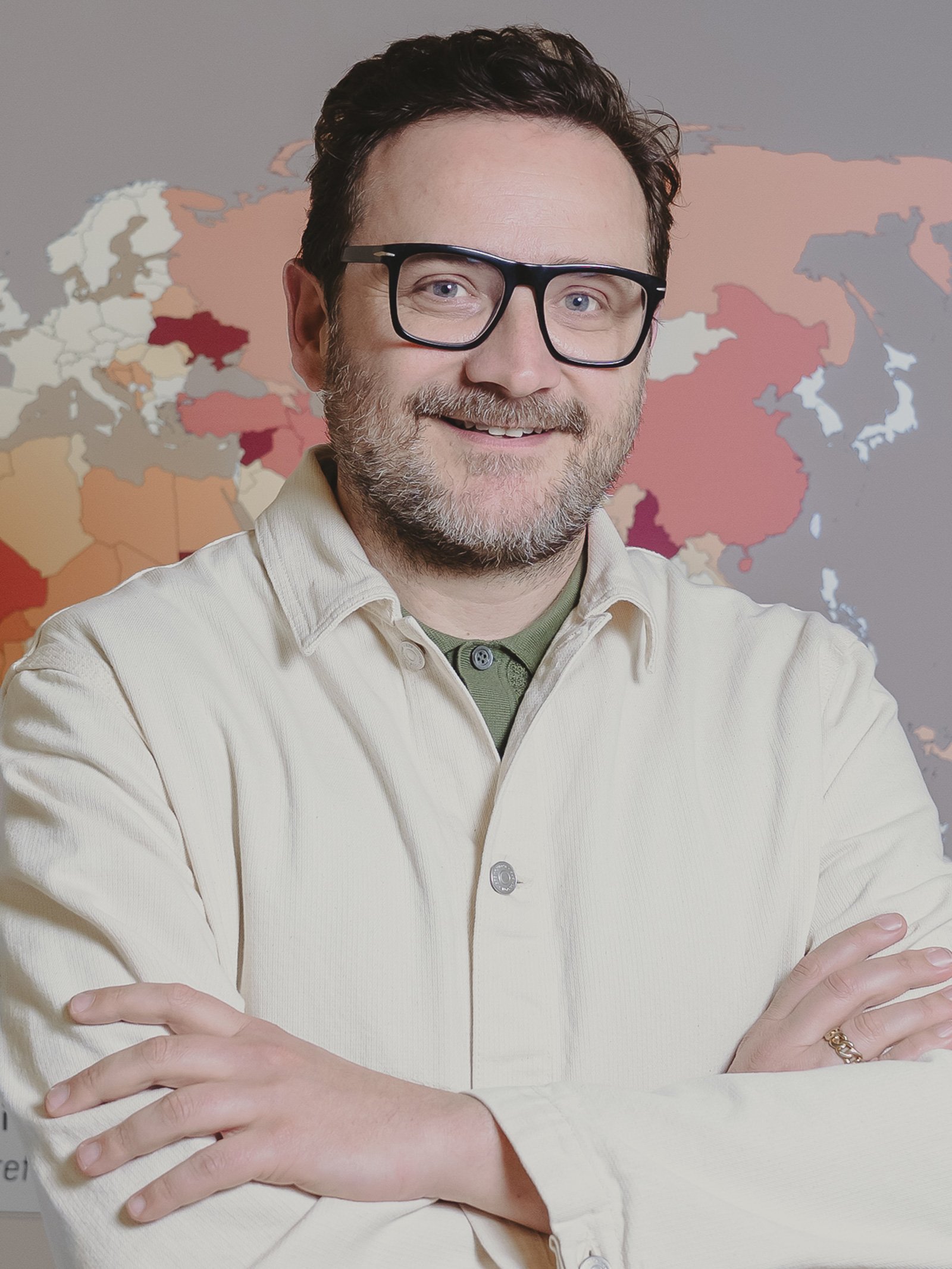 A portrait of Triennale curator Marco Sammicheli wearing a white chore coat and black glasses.