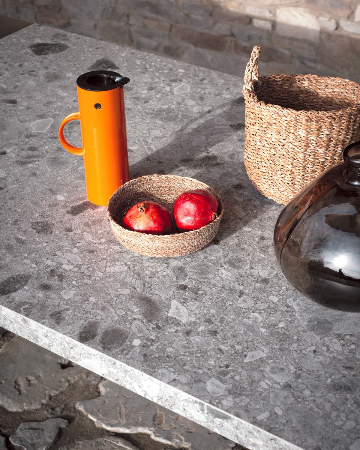 Grey stone countertop with orange pitcher and fruit bowl