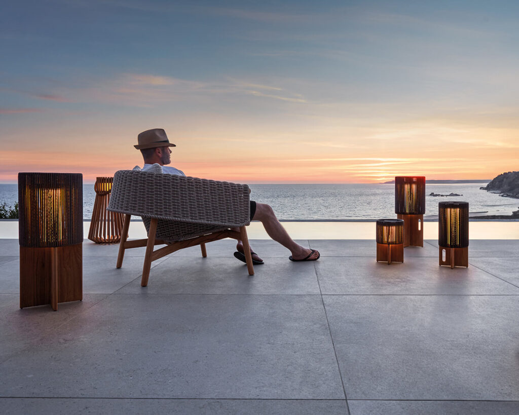 Man sits in outdoor lounge chair surrounded by lanterns