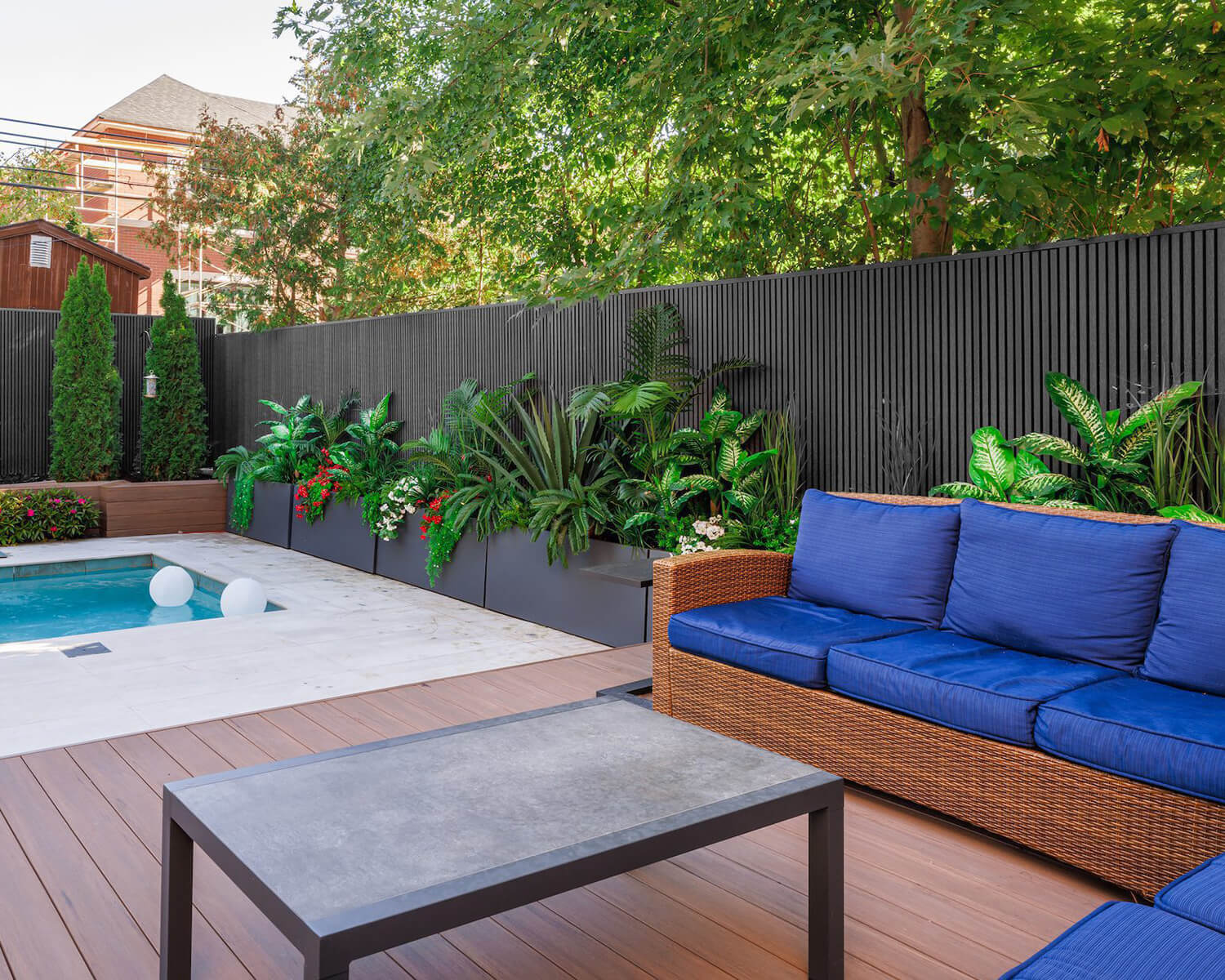 Backyard with brown deck, black fence and blue sofa