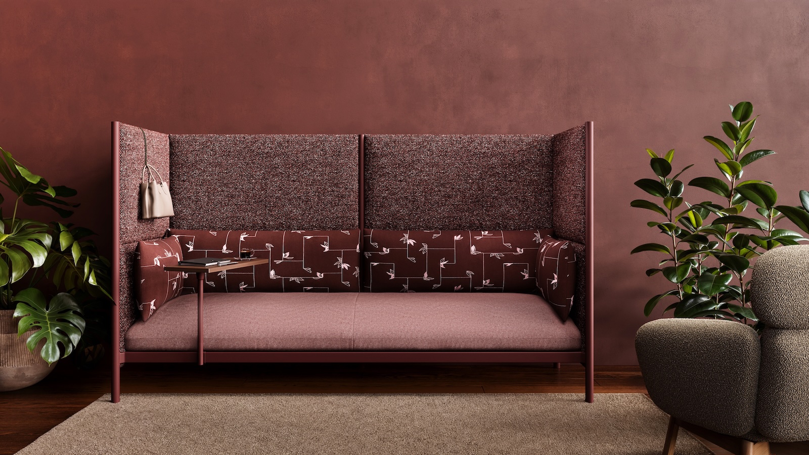A modern maroon sofa with patterned upholstery and high side panels is placed against a dark red wall, flanked by green potted plants and a small side table.