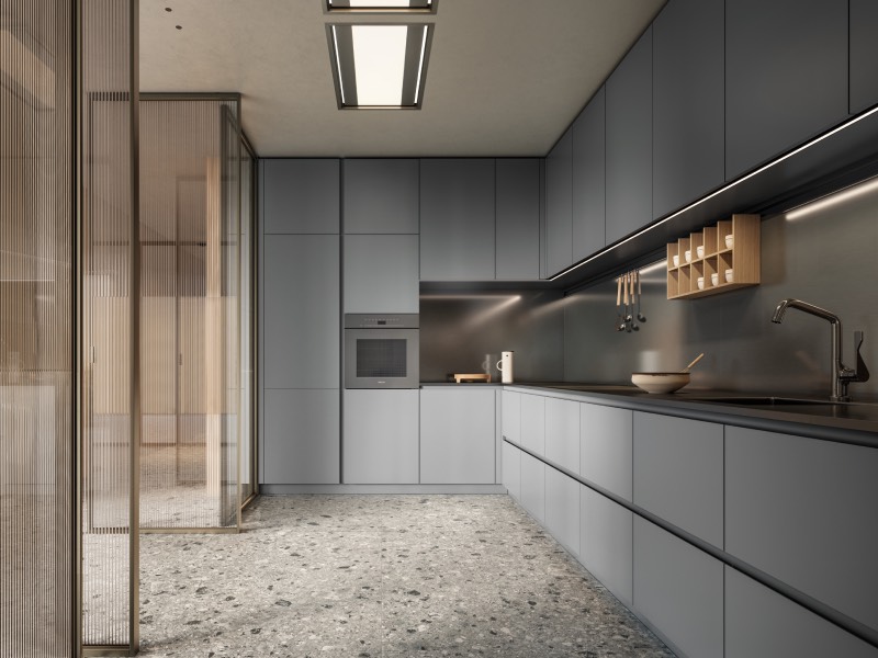 Modern kitchen with sleek matte gray cabinets, built-in oven, minimalist fixtures, and terrazzo flooring. Glass partition separates the kitchen from an adjacent room.