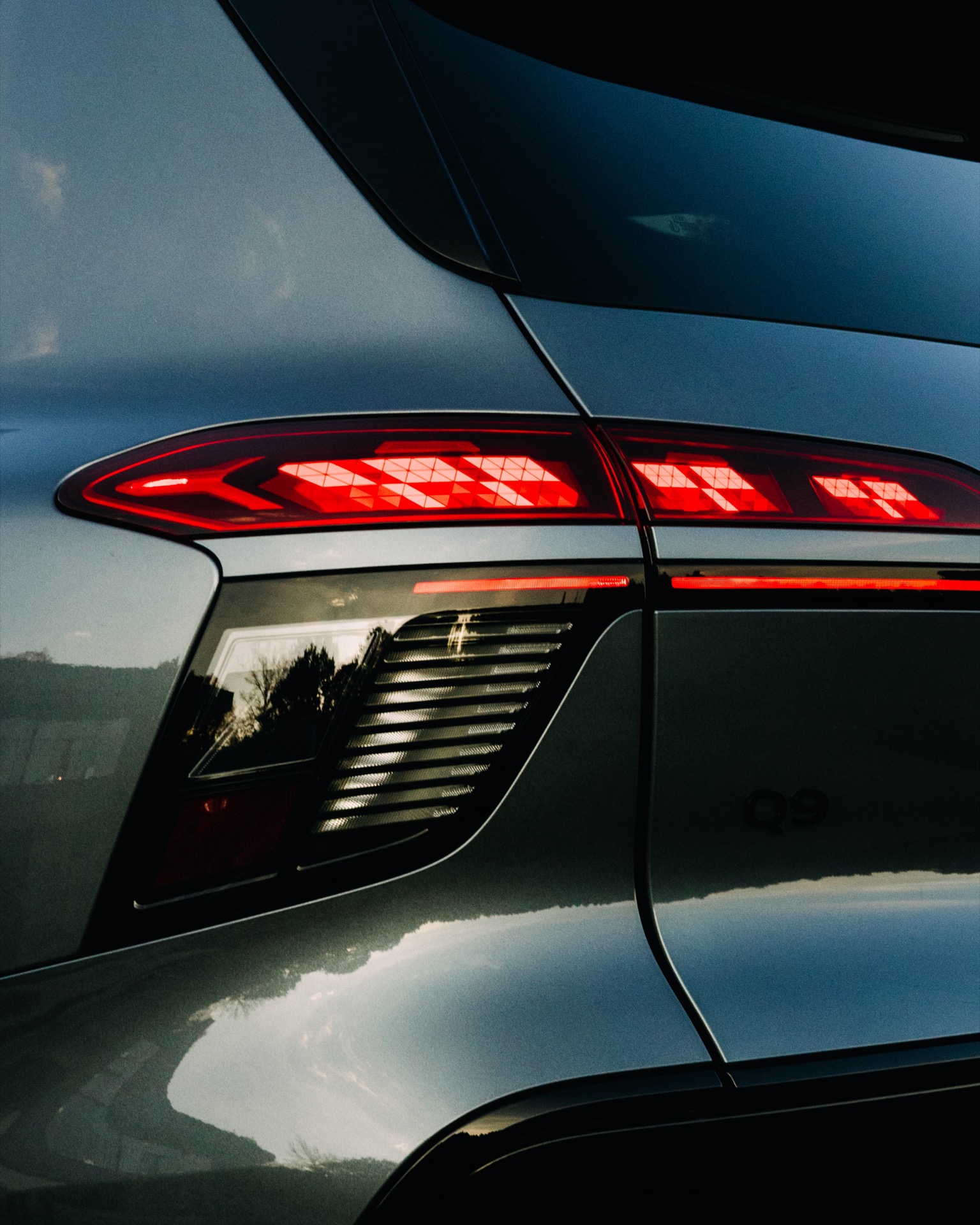 Close-up of the rear taillight and Audi Q9 badge on a grey SUV.